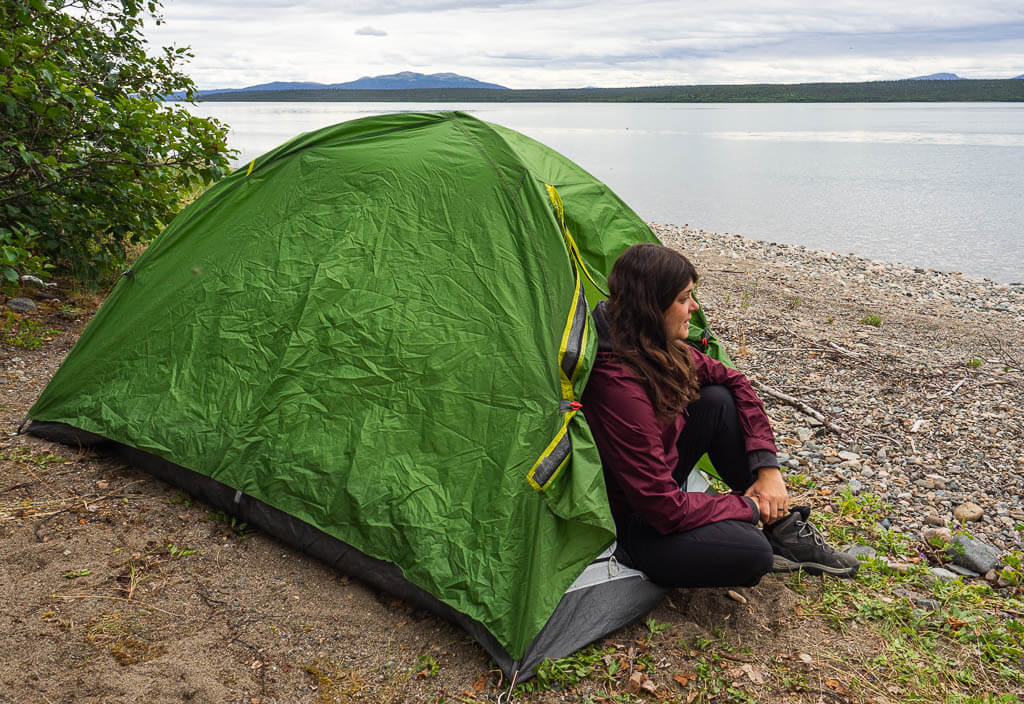 Dana sitting in a tent at a lake