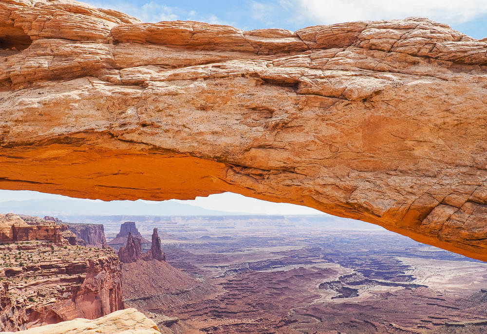 Mesa Arch with canyon landscape in the background