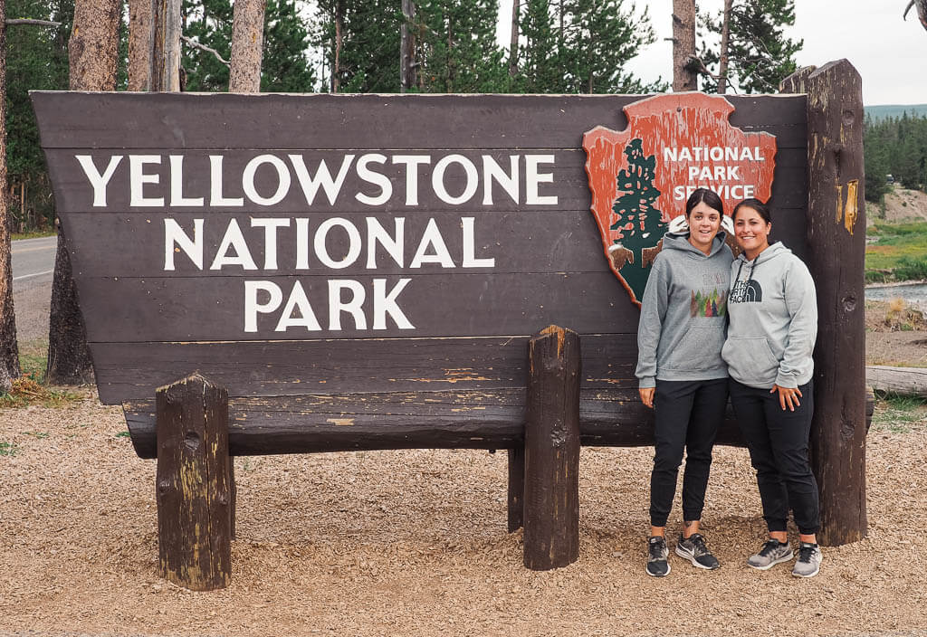 Us standing in front of the Yellowstone National Park sign