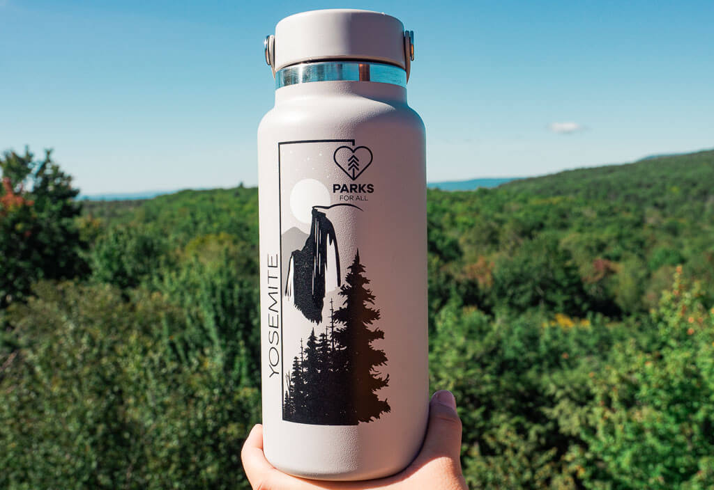 Hydroflask bottle in front of a lush forest