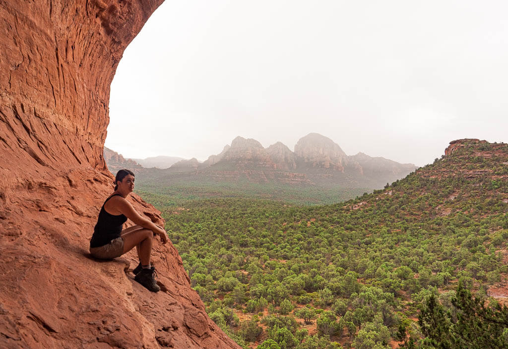 Dana sitting at the edge of the Birthing Cave Sedona, one of the most unique Sedona caverns