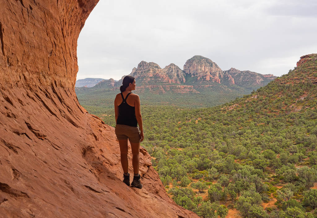 Dana standing on the edge of Birthing Cave, a unique cave in Sedona