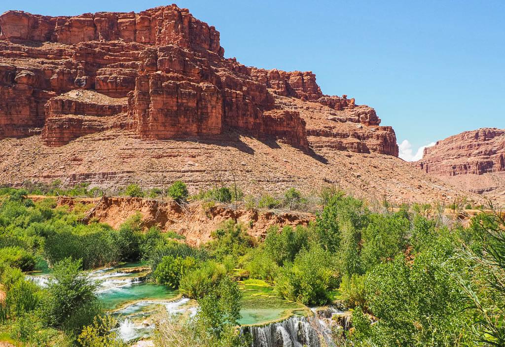 Turquoise Navajo Falls in front of rock formation