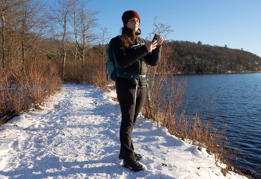 Dana using a hiking app on a winter hike