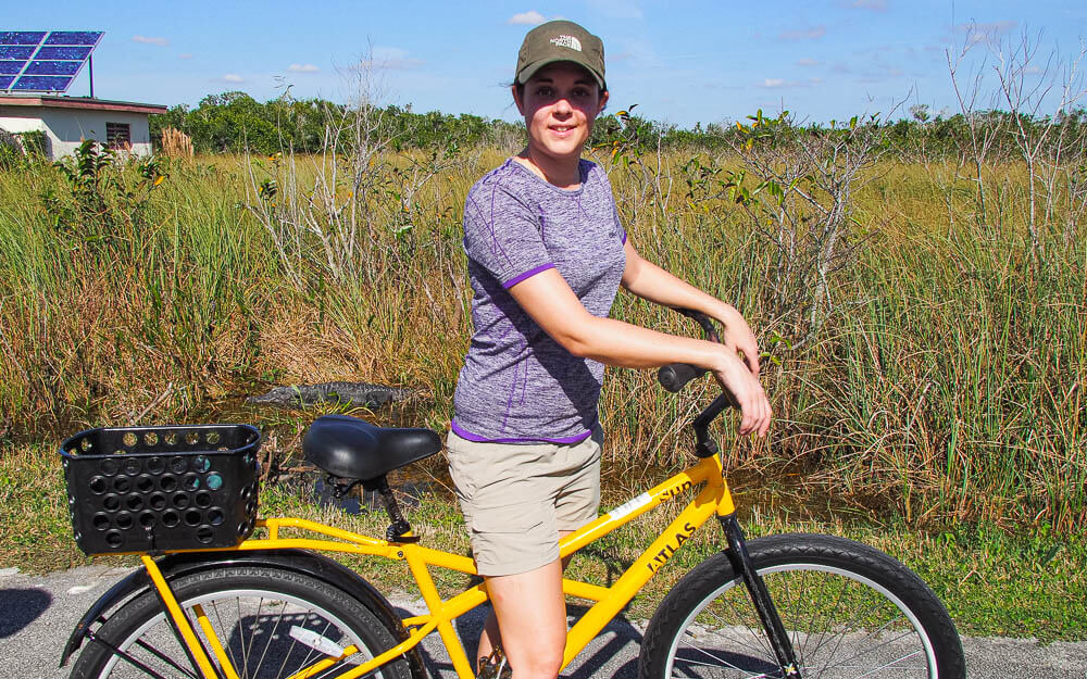 Dana riding a bike next to an alligator in Shark Valley