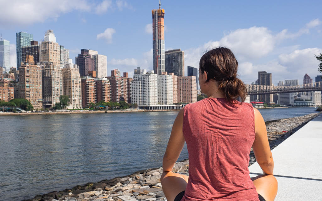 Dana sitting on Roosevelt Island looking at the Manhattan skyline