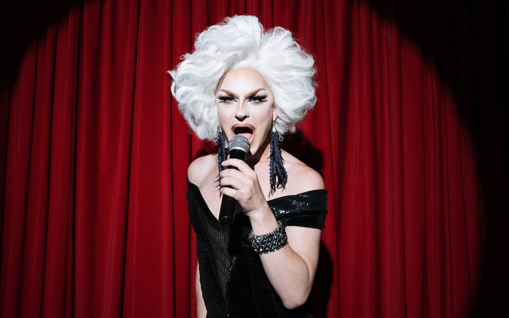 Drag Queen in front of a red curtain